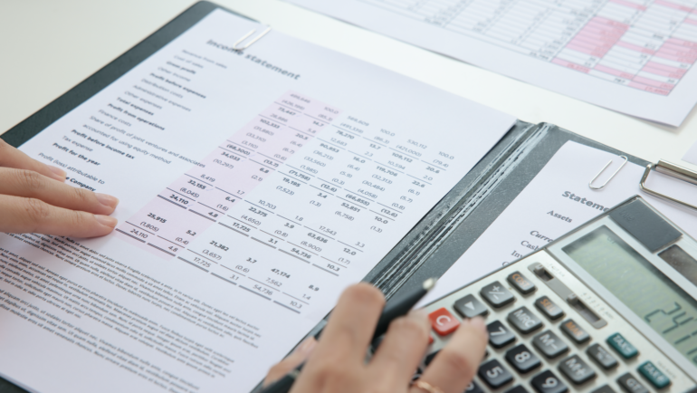 Person reviewing financial statements with a calculator